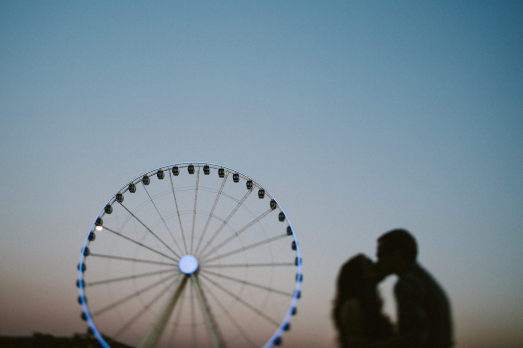 couple kissing at the seattle waterfront with ferris wheel in the background