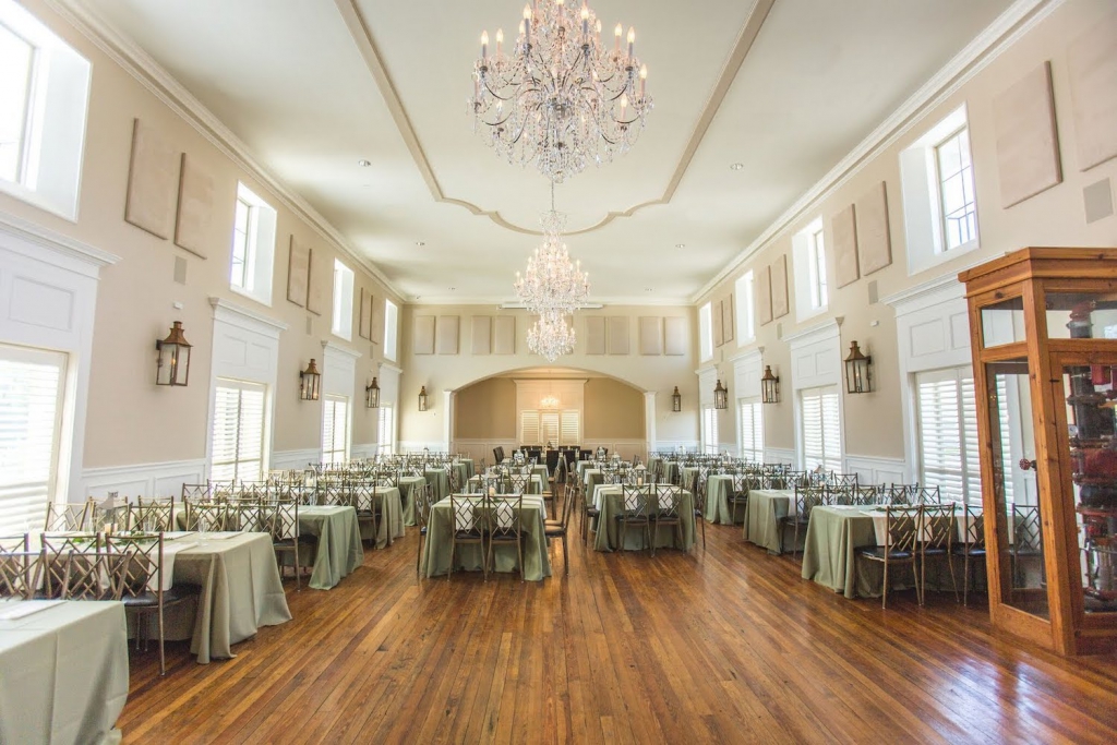 interior of the Grande Ballroom in the Milltown Historic District in New Braunfels, with three chandeliers shining down on tables set for a wedding reception