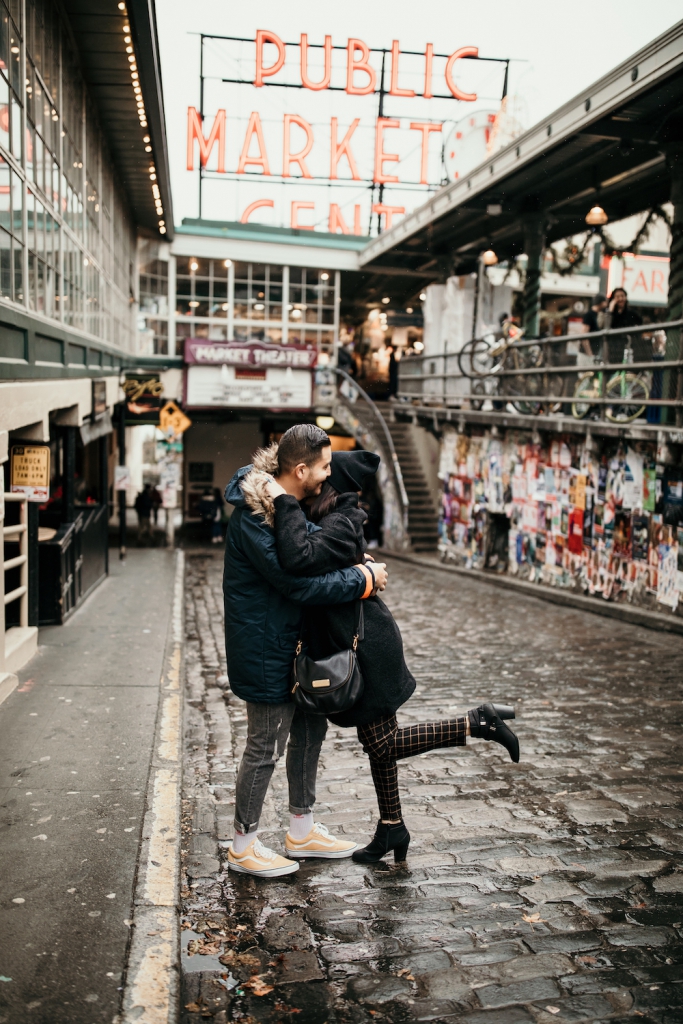 couple hugging at pike place market in seattle on a rainy day