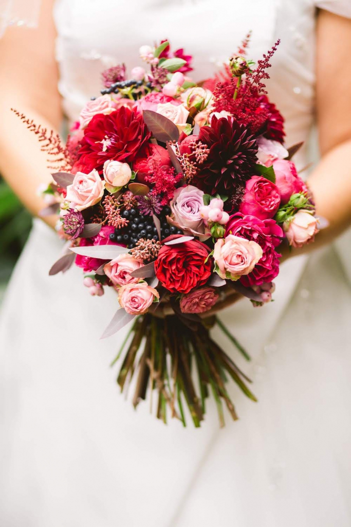 Bride holding bouquet with red and pink flowers