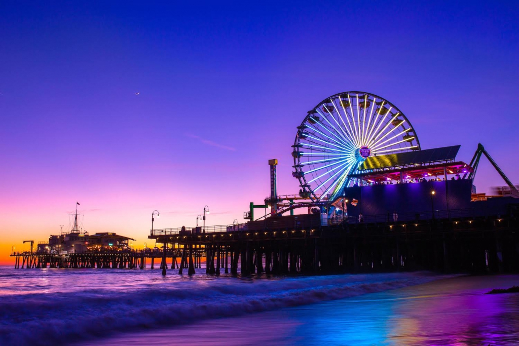 santa monica pier ferris wheel lit up during a purple, pink, and orange sunset in california