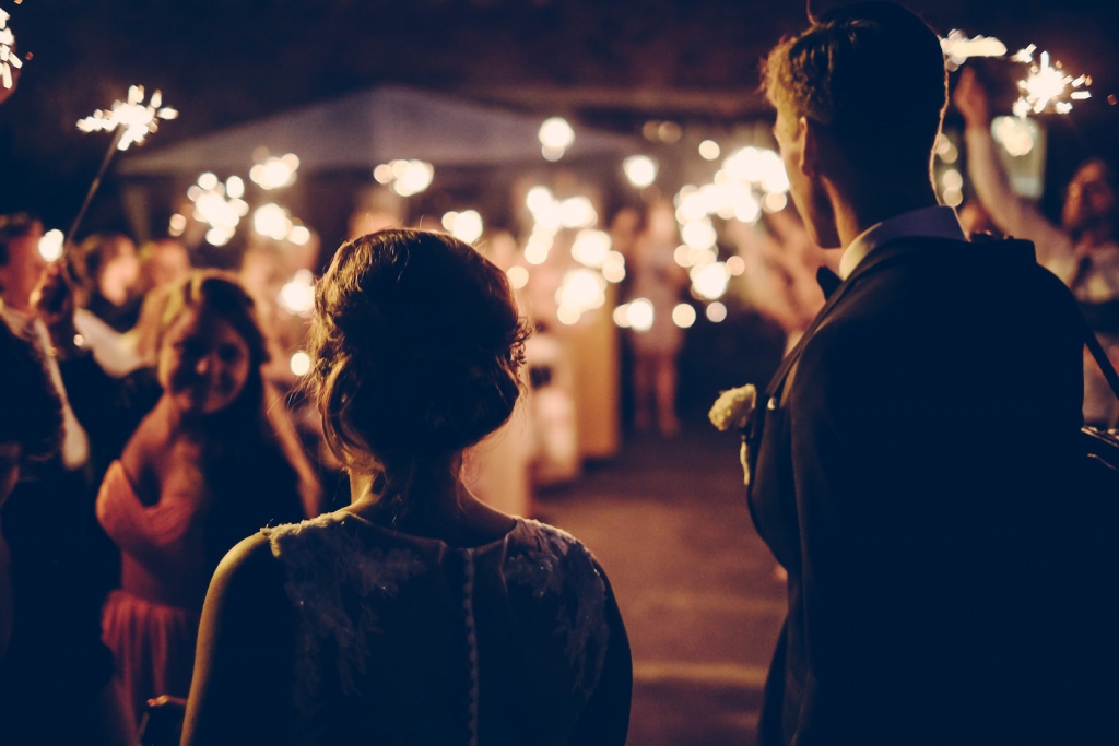 Bride and groom walking with wedding guests holding sparklers